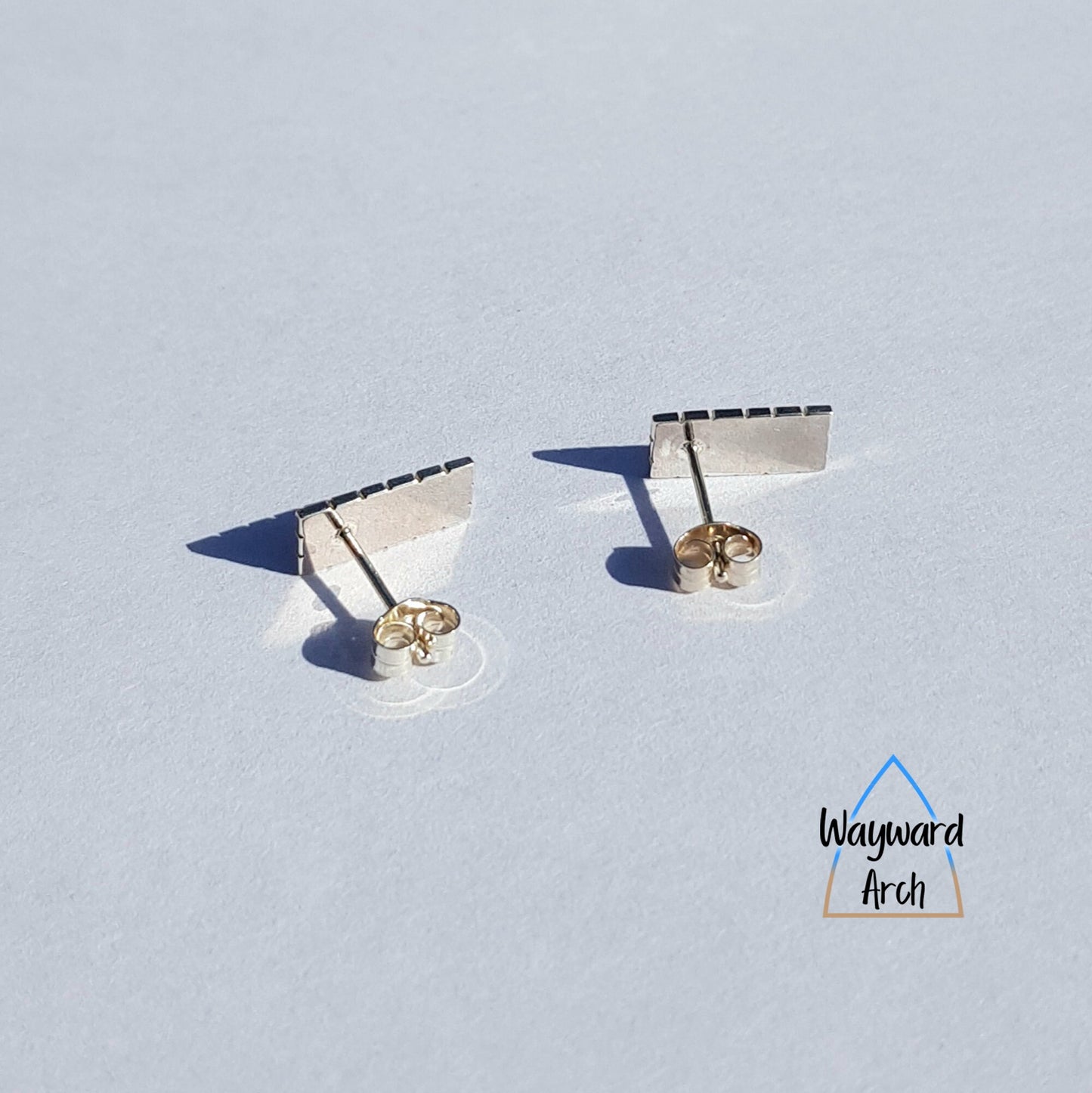 Back view of sterling silver rectangular stud earrings with smooth polished finish and straight posts attached at one end of the rectangle and with butterfly scrolls