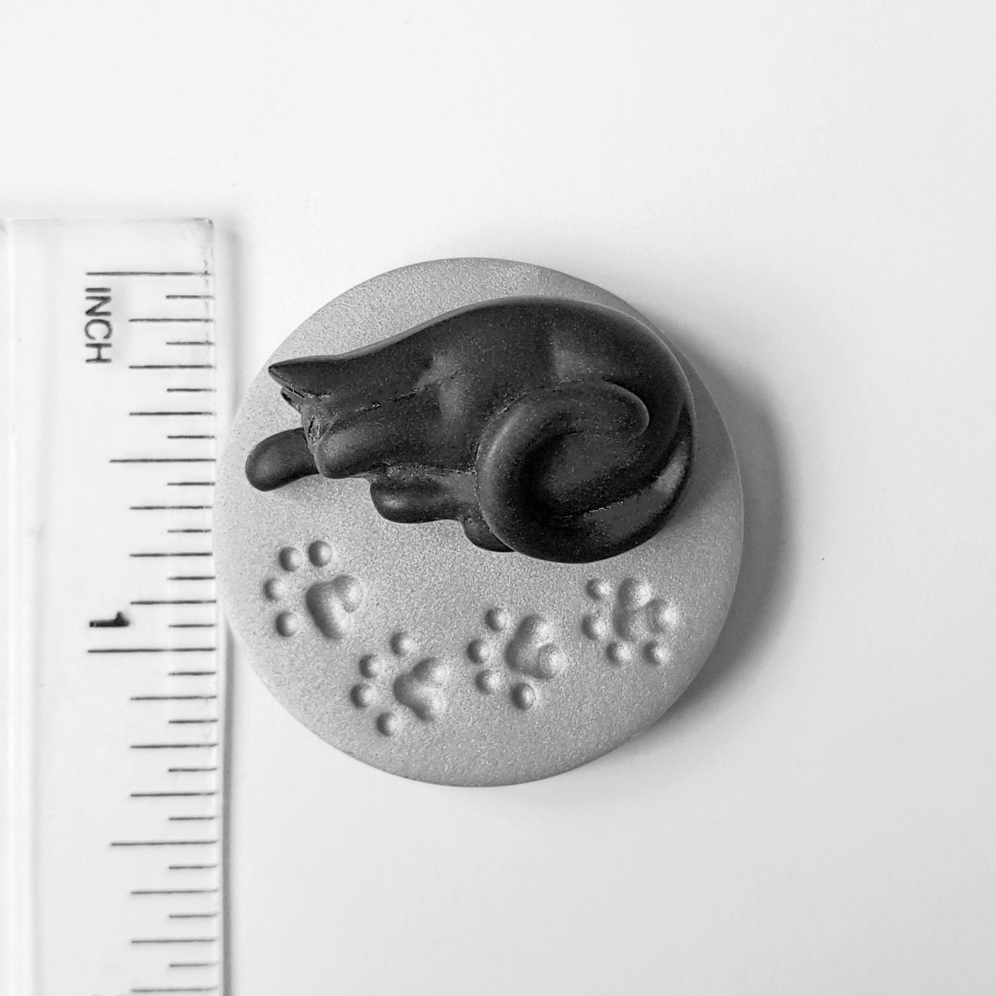 The black cat needle minder is 3.5 centimetres across or just under 1.5 inches. 