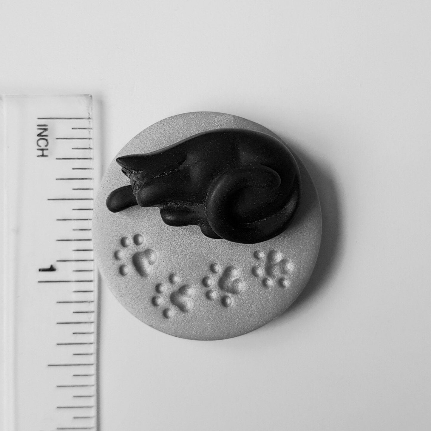 The black cat needle minder is 3.5 centimetres across or just under 1.5 inches.