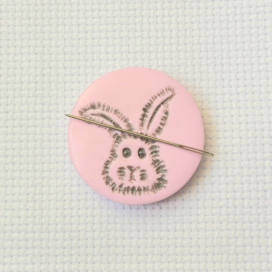 Light pink needle minder with grey bunny head imprinted design.