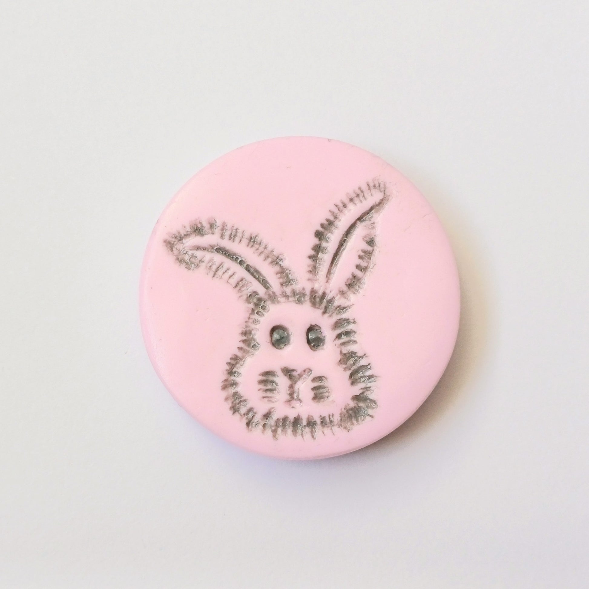 Light pink needle minder with grey bunny head imprinted design.