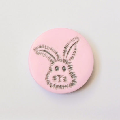 Light pink needle minder with grey bunny head imprinted design.