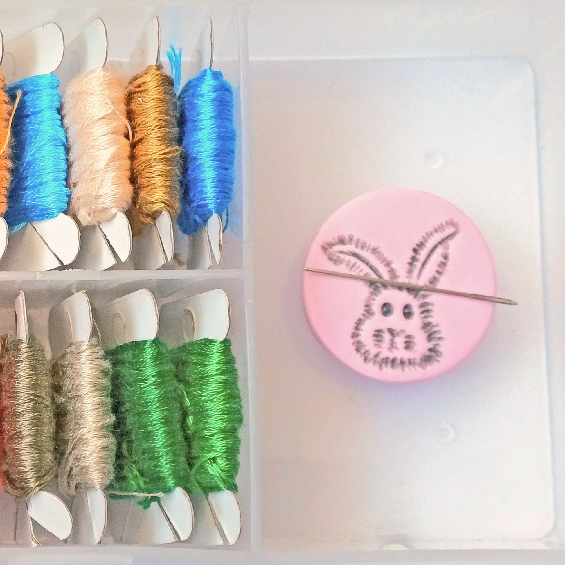 Light pink needle minder with grey bunny head imprinted design.