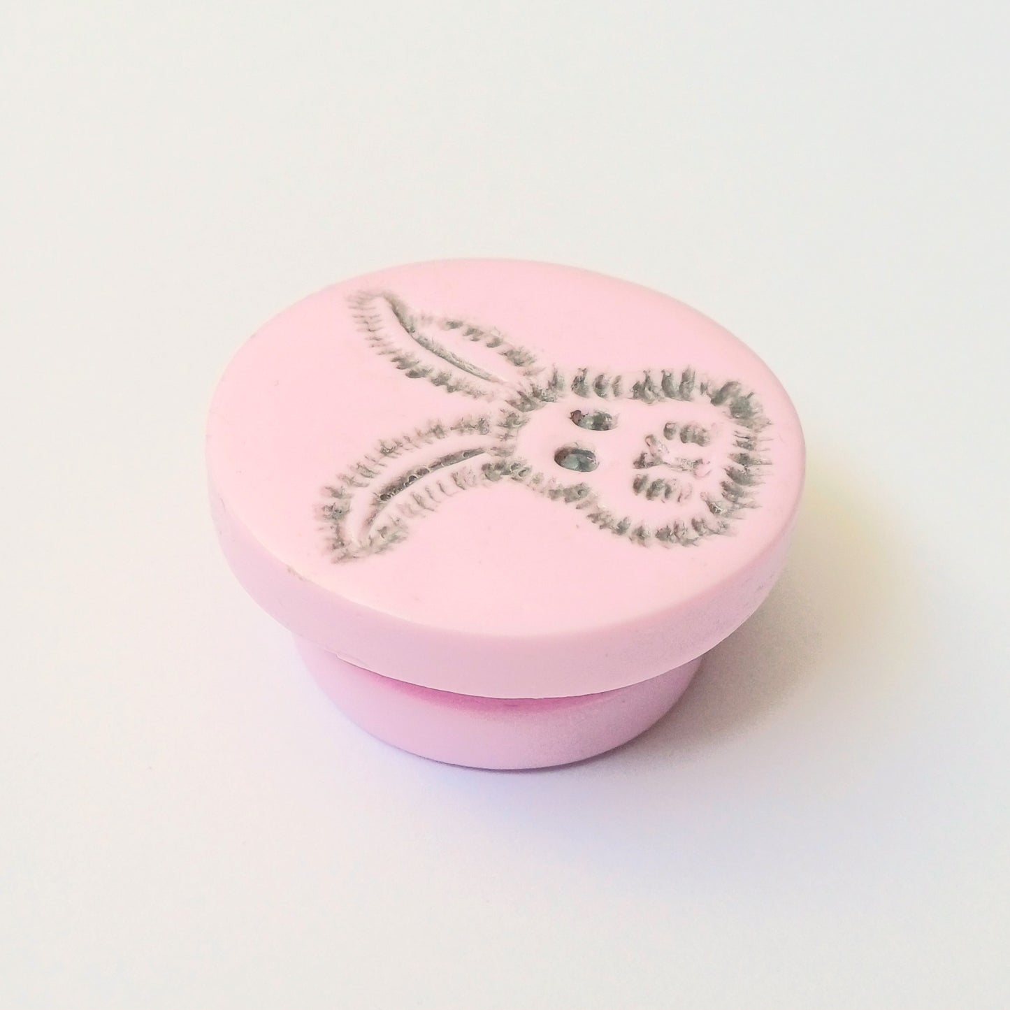 Light pink needle minder with grey bunny head imprinted design.