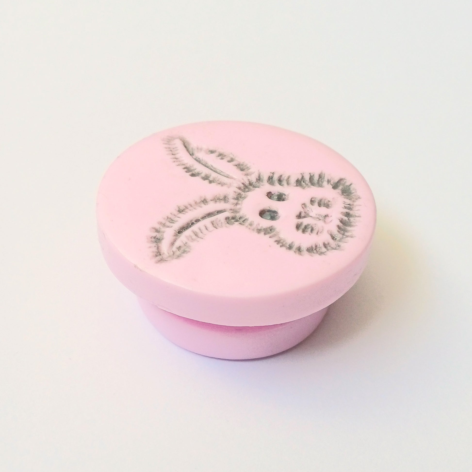 Light pink needle minder with grey bunny head imprinted design.