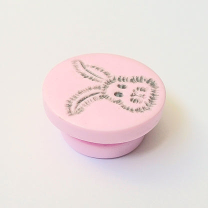 Light pink needle minder with grey bunny head imprinted design.