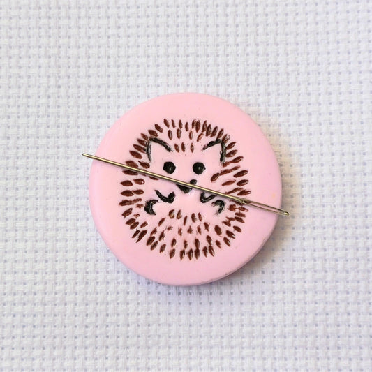 Light pink needle minder with brown and black hedgehog imprinted design.