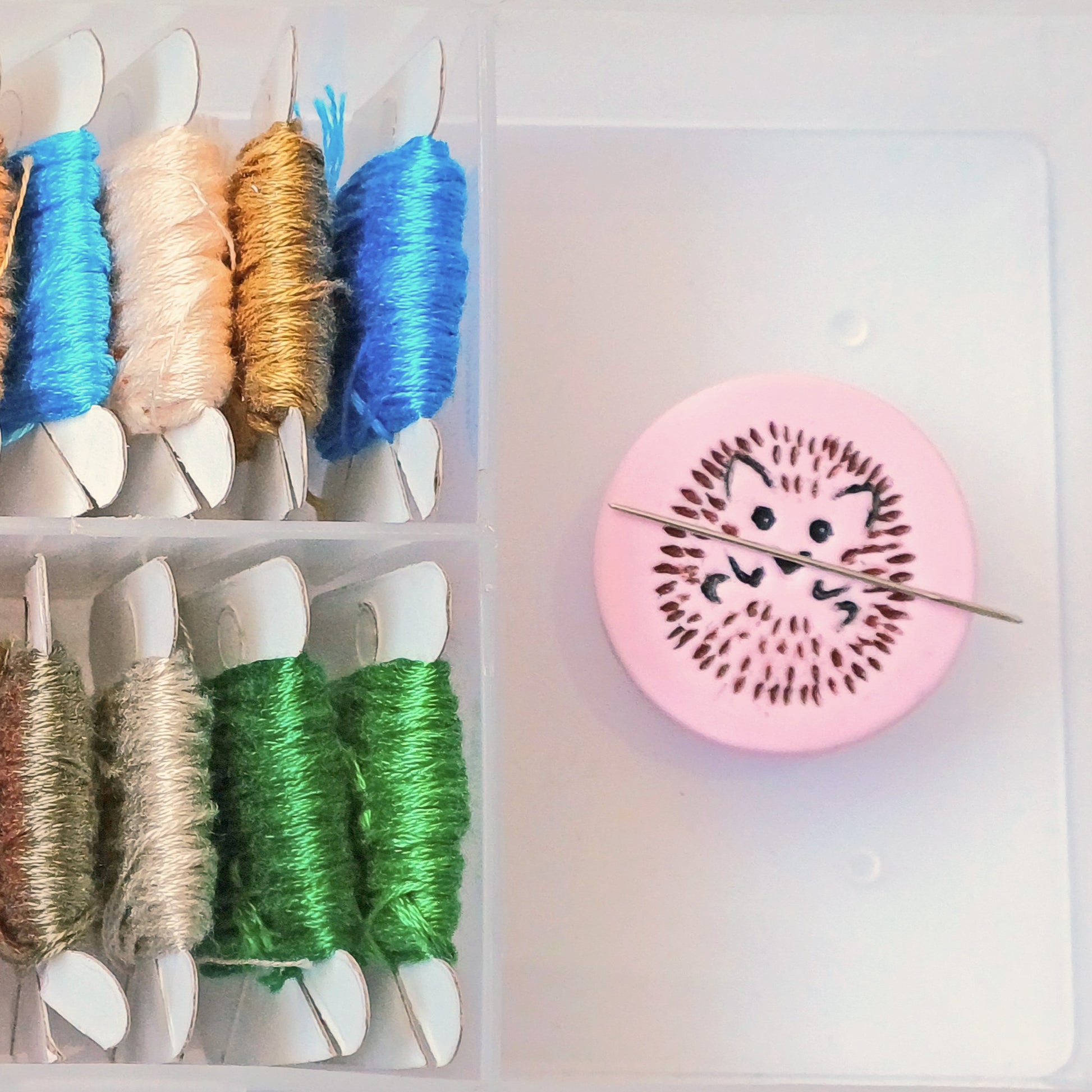 Light pink needle minder with brown and black hedgehog imprinted design.