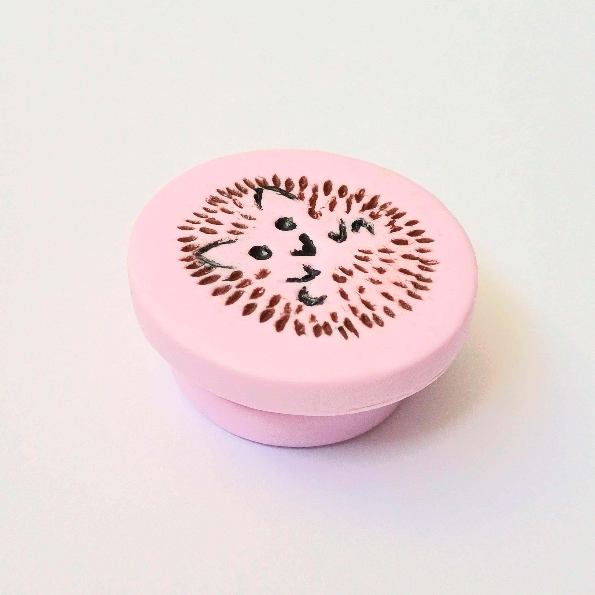 Light pink needle minder with brown and black hedgehog imprinted design.