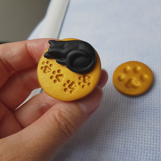 Video of black cat needle minder and gold paw print needle minder set for cross stitch.