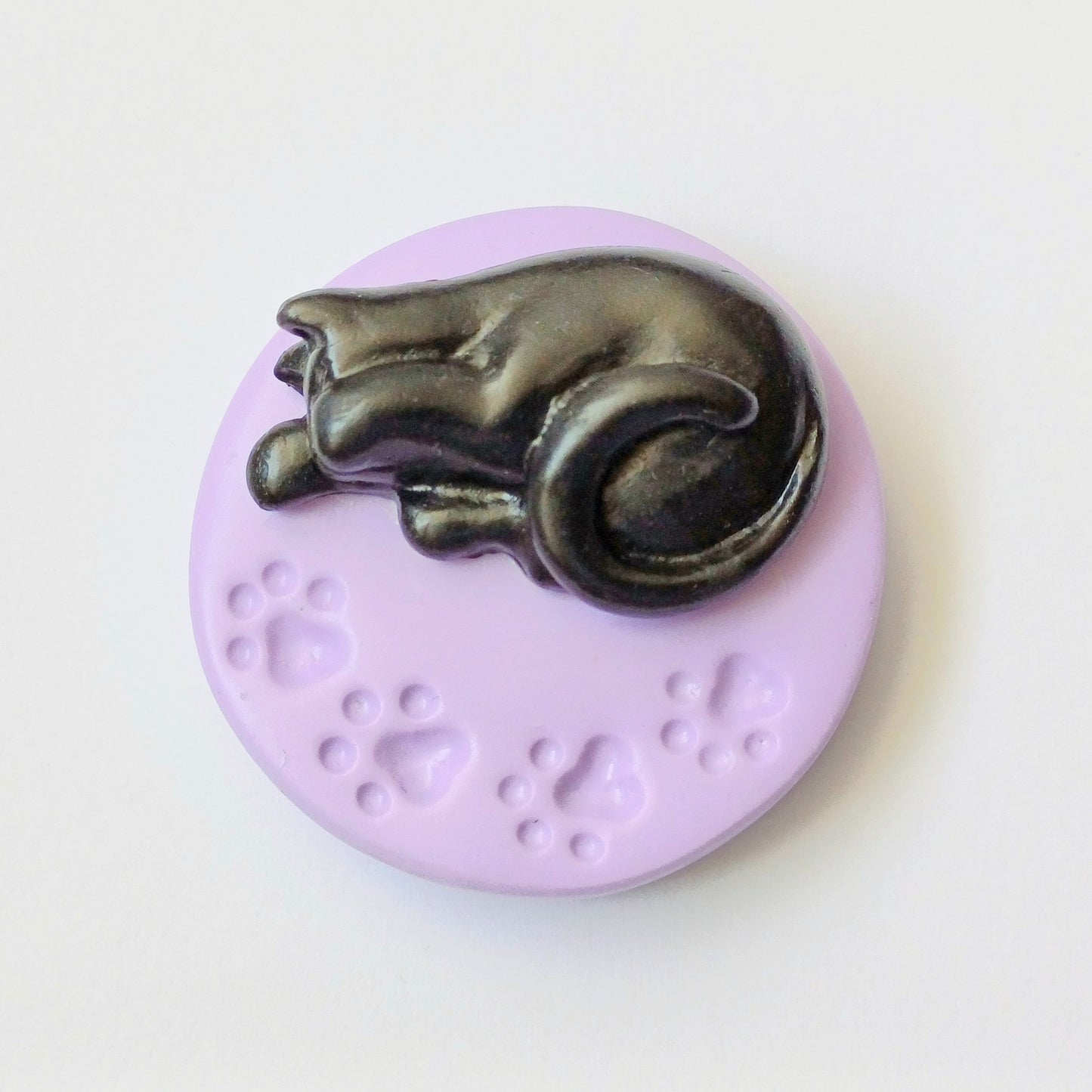 Black cat on purple paw print base needle minder for cross stitching.