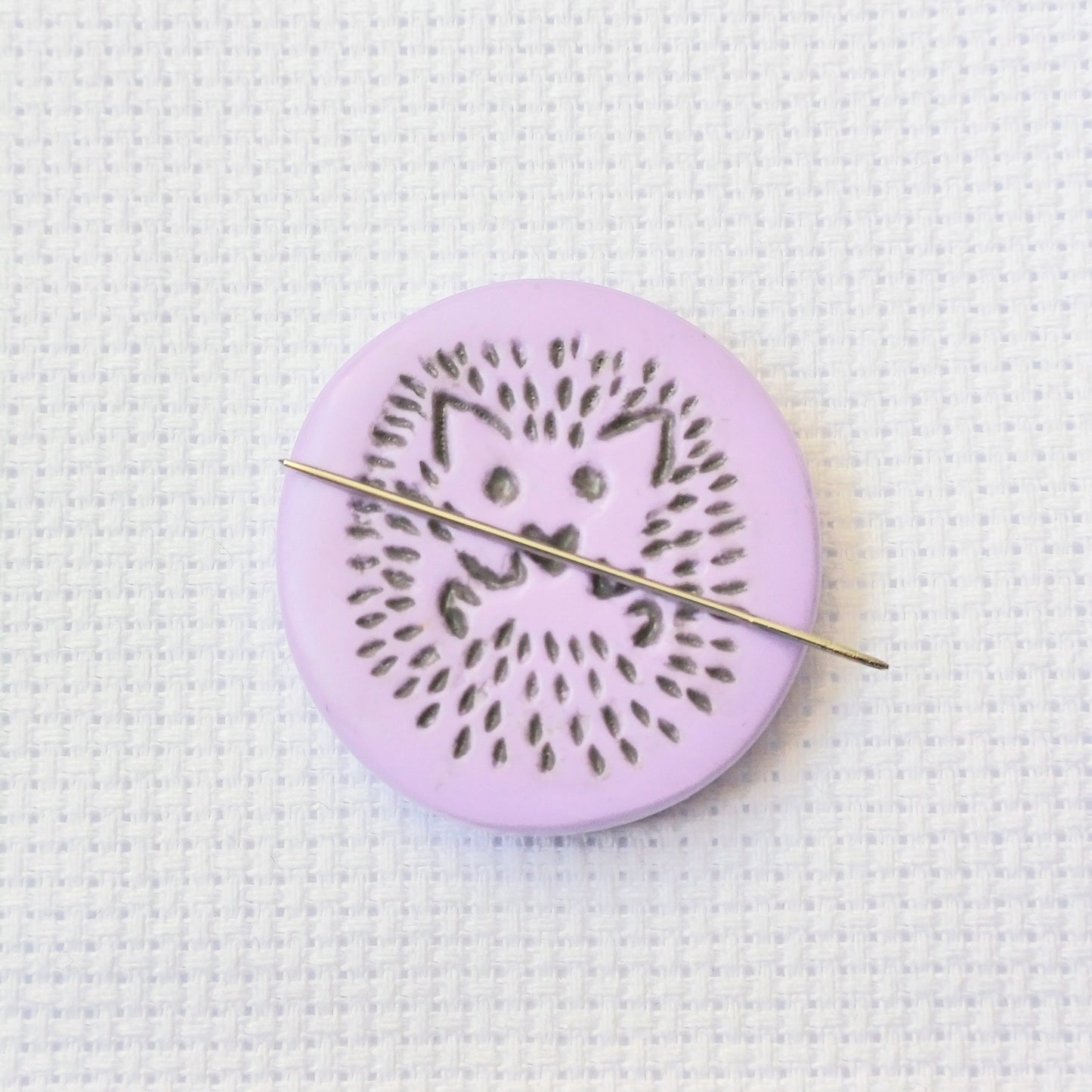 Purple needle minder with grey hedgehog imprinted design.