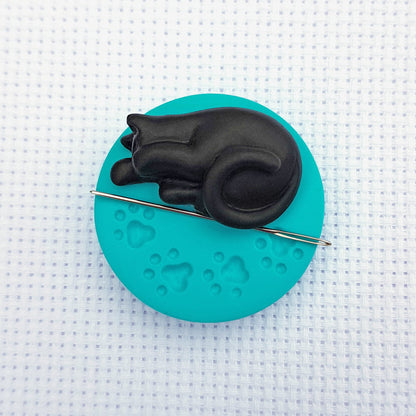 Black cat on blue paw print base needle minder for cross stitching.